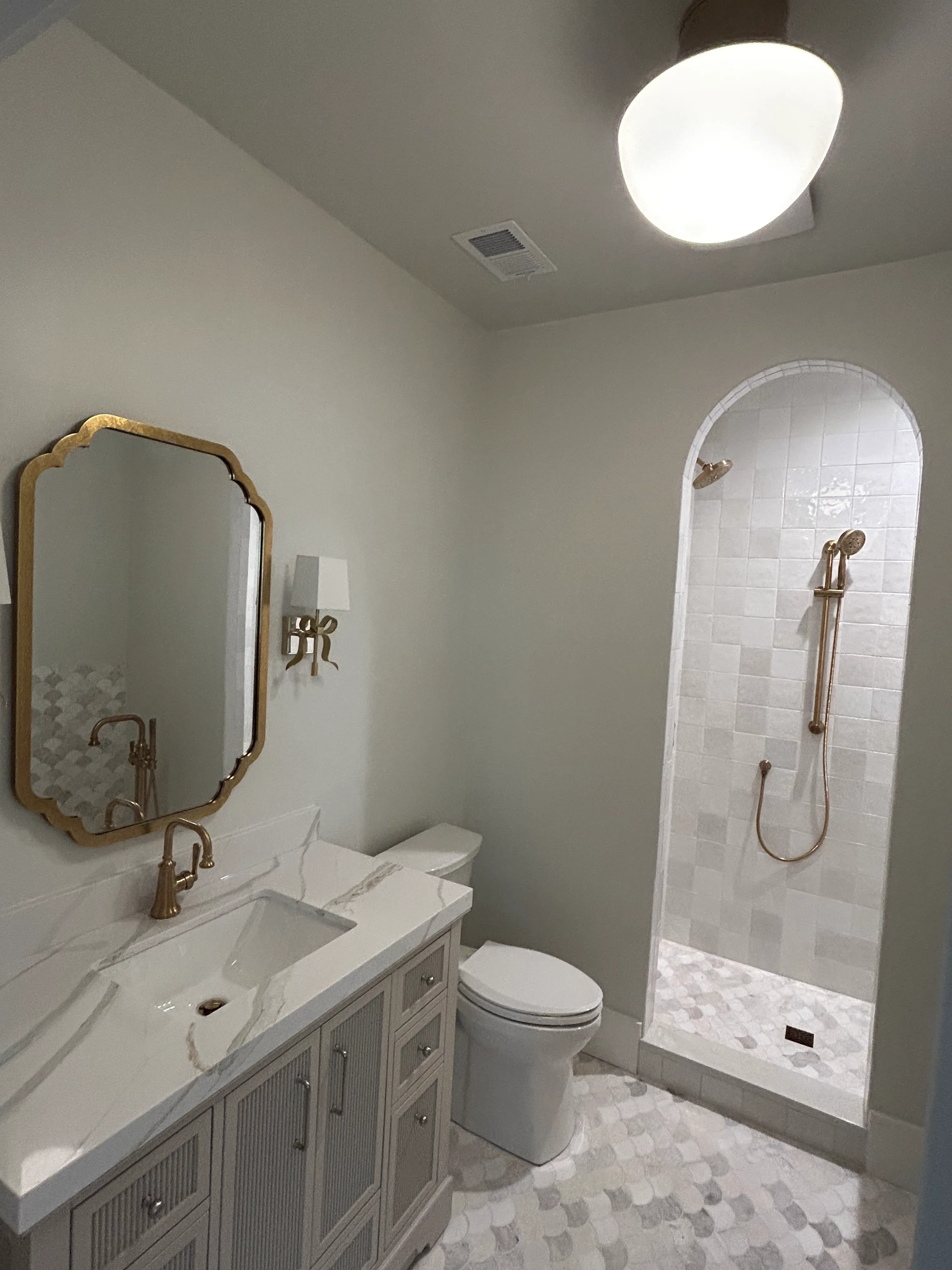 Bathroom remodel with gold fixtures, marble vanity and tiled shower by Picture Perfect HHI