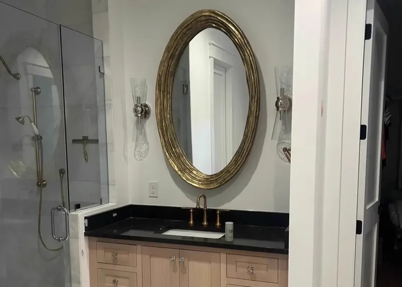 Bathroom vanity with oval gold mirror and glass sconces