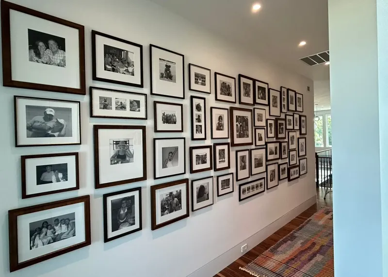 Large black and white photo gallery wall spanning a hallway