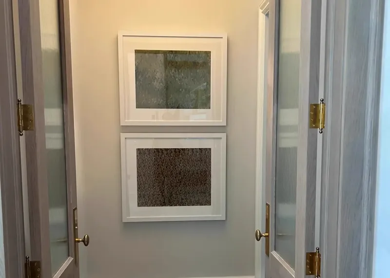 Hallway with two framed art pieces between glass doors and pendant light