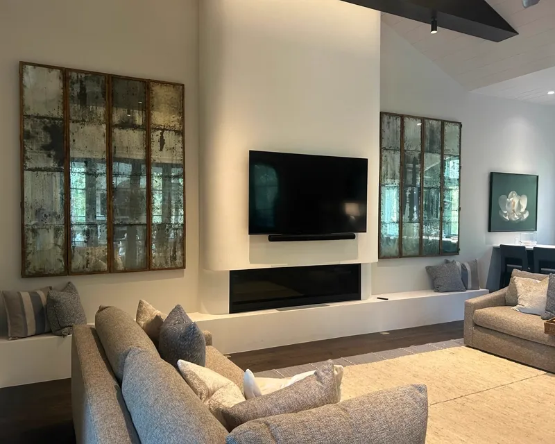 Living room with TV mount, soundbar, and large art panels flanking fireplace