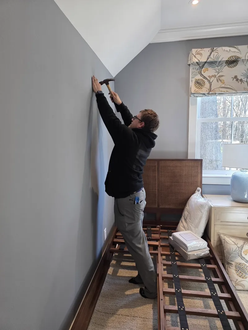 Picture Perfect team member hanging hardware in a client's bedroom