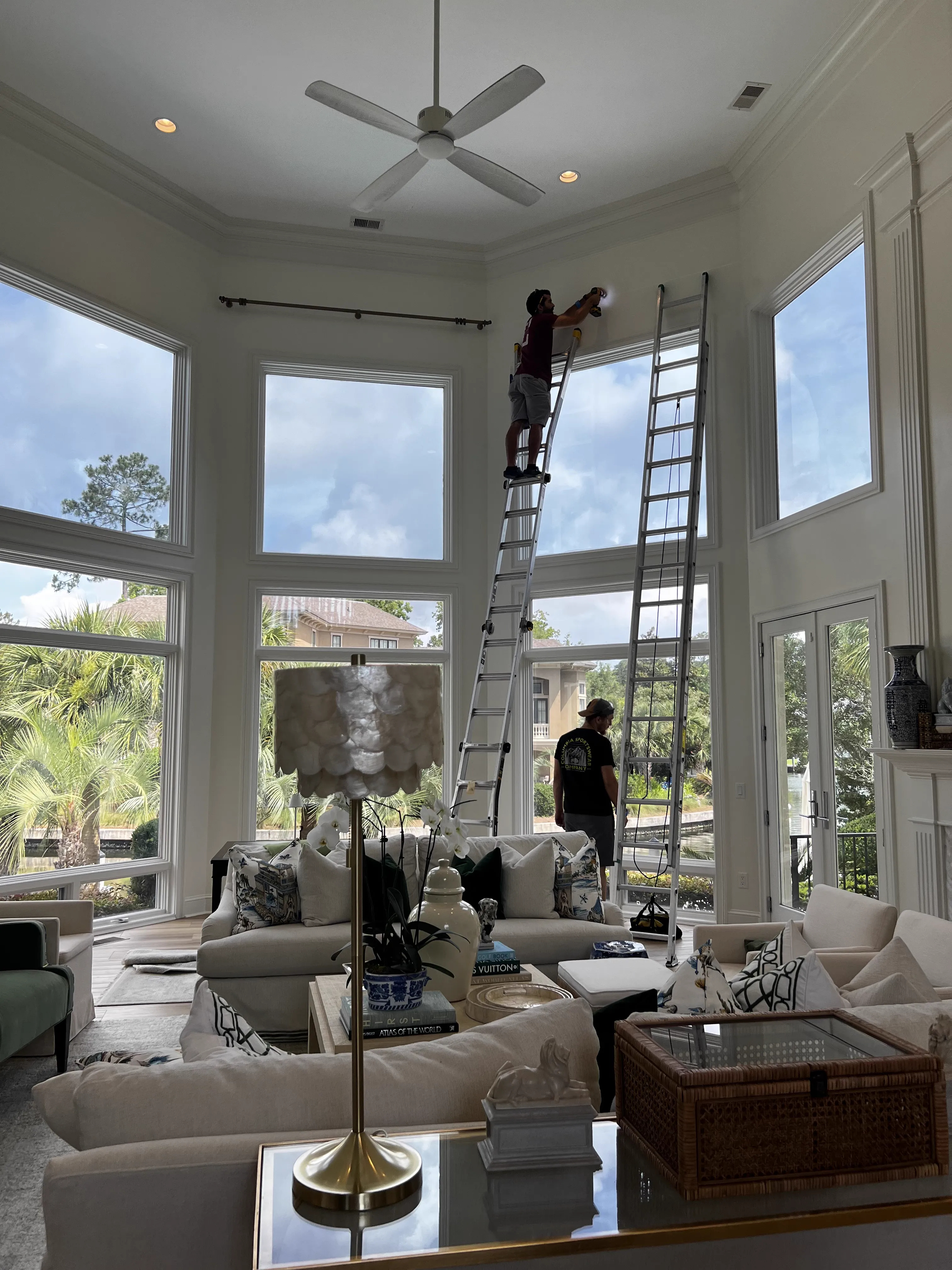 Picture Perfect team on ladders installing in a high-ceiling living room